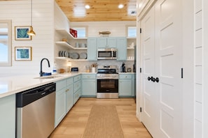Una cocina con armarios azul claro, electrodomésticos de acero inoxidable y techo de madera.