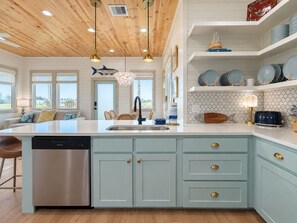 Una cocina moderna con una isla central, lavavajillas de acero inoxidable y armarios azul claro.