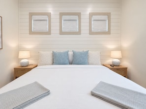 Een hotelkamer met een groot bed, twee nachtkastjes en drie aan de muur bevestigde fotolijstjes.