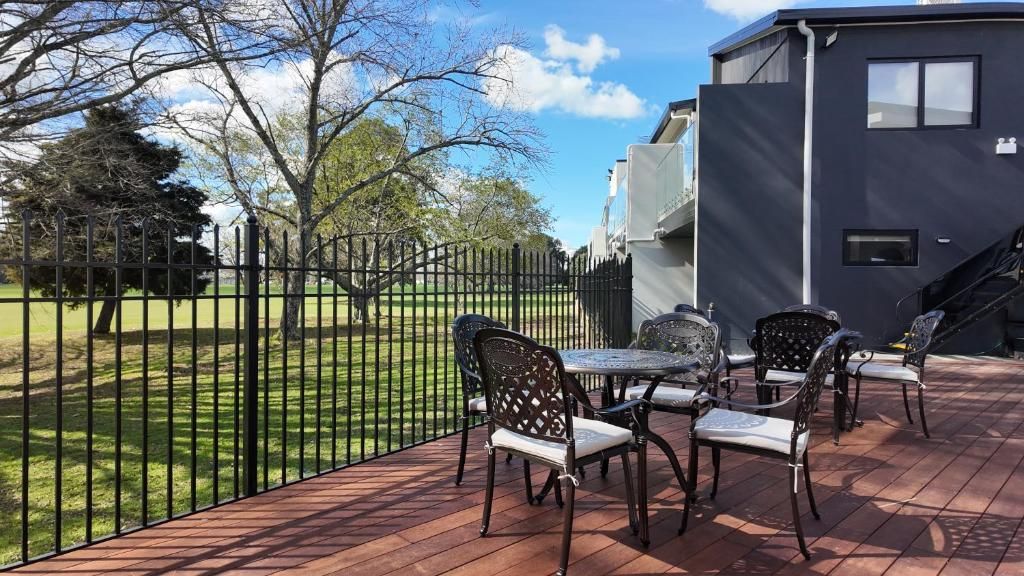 Eine Terrasse mit Gartenmöbeln, einem Zaun und einem Gebäude im Hintergrund.
