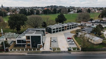Un edificio moderno con un estacionamiento y un campo verde al fondo.