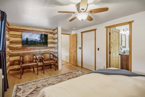 A bedroom with a bed, a ceiling fan, a wooden wall, a door, and a window. - Fall Escape Special: 15% Discount Ends Nov 30! Must book by Oct 18 (Pagosa Springs)