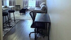A living room with a sofa, a dining table, and a kitchen area with a bar counter. - Prime 1-bedroom apartment in Uptown Charlotte with Pool and gym (Charlotte)