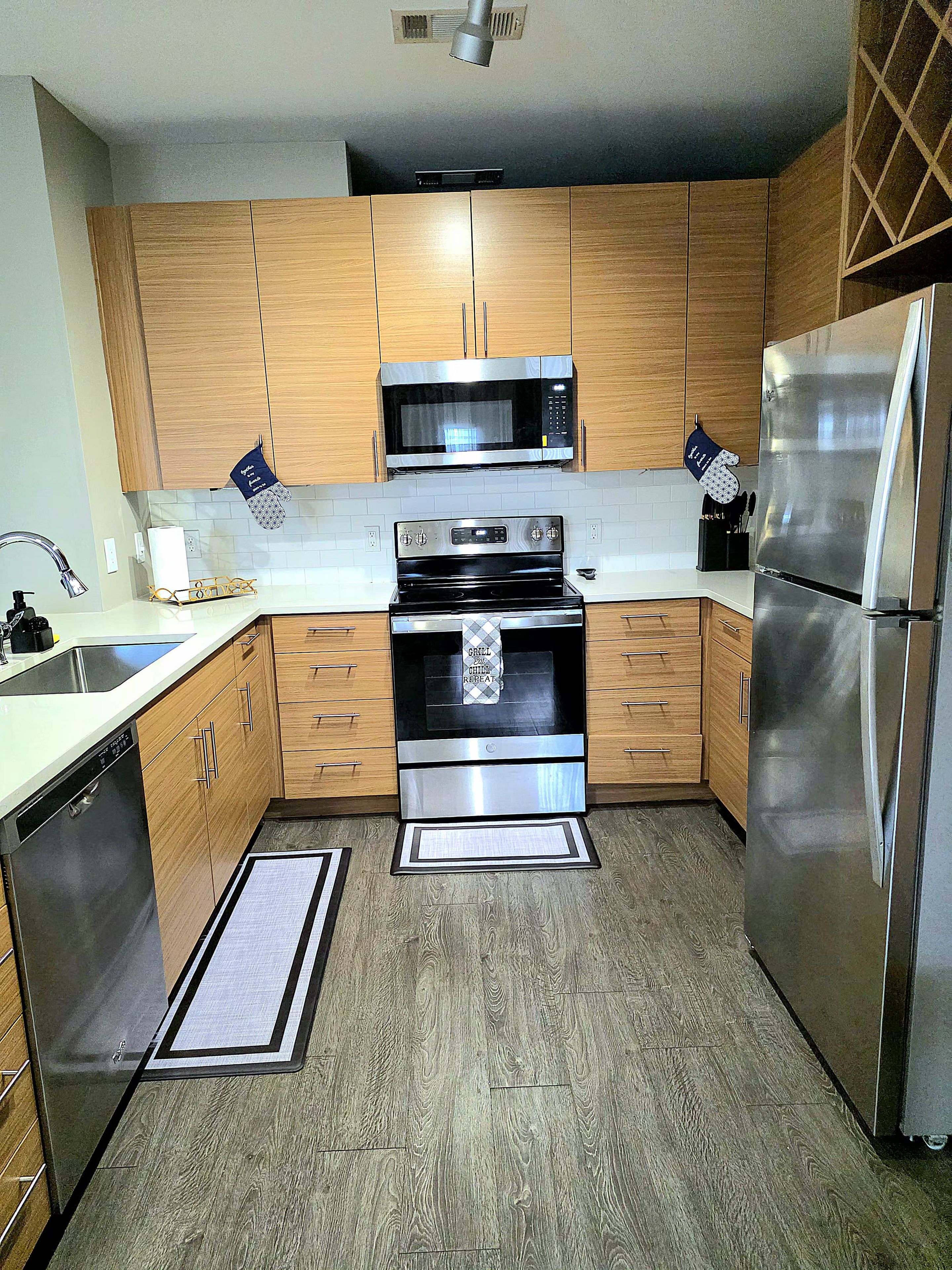 A modern kitchen with wooden cabinets, stainless steel appliances, and a dishwasher.
