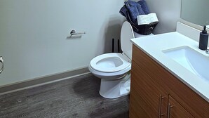 A bathroom with a toilet, sink, mirror, towel rack, and a basket. - Prime 1-bedroom apartment in Uptown Charlotte with Pool and gym (Charlotte)