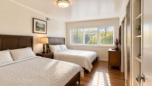 A bedroom with two beds, a nightstand with a lamp, a window with blinds, and a door with a plant. - Work & Relax Retreat, Pool, Wifi, Stocked Kitchen (Nashville)