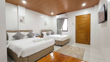Une chambre d’hôtel avec deux lits, un plafond en bois, une télévision et une porte.