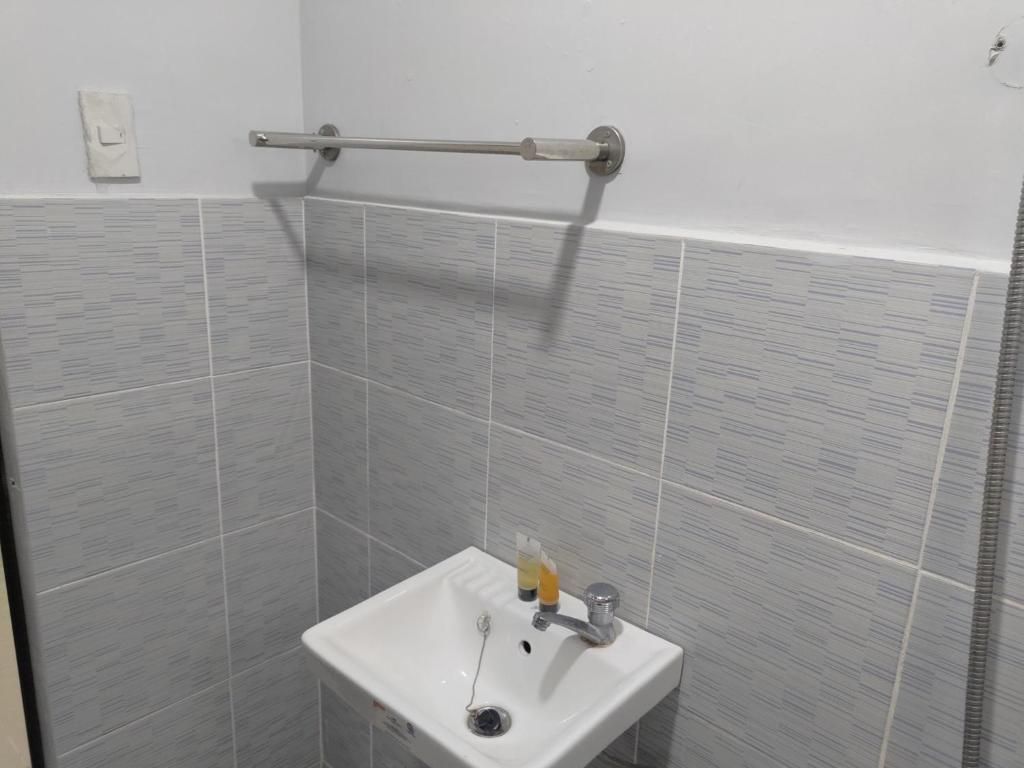 Un baño con lavamanos blanco, toallero y baldosas grises estampadas.