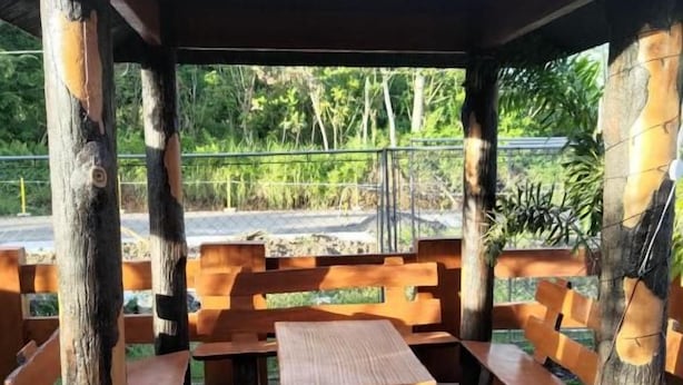 Un área de estar al aire libre con bancos de madera y una mesa bajo una protección.