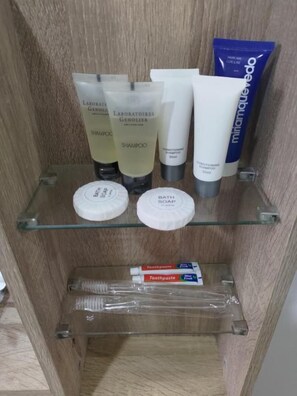 A bathroom shelf with toiletries including shampoo, conditioner, and soap.
