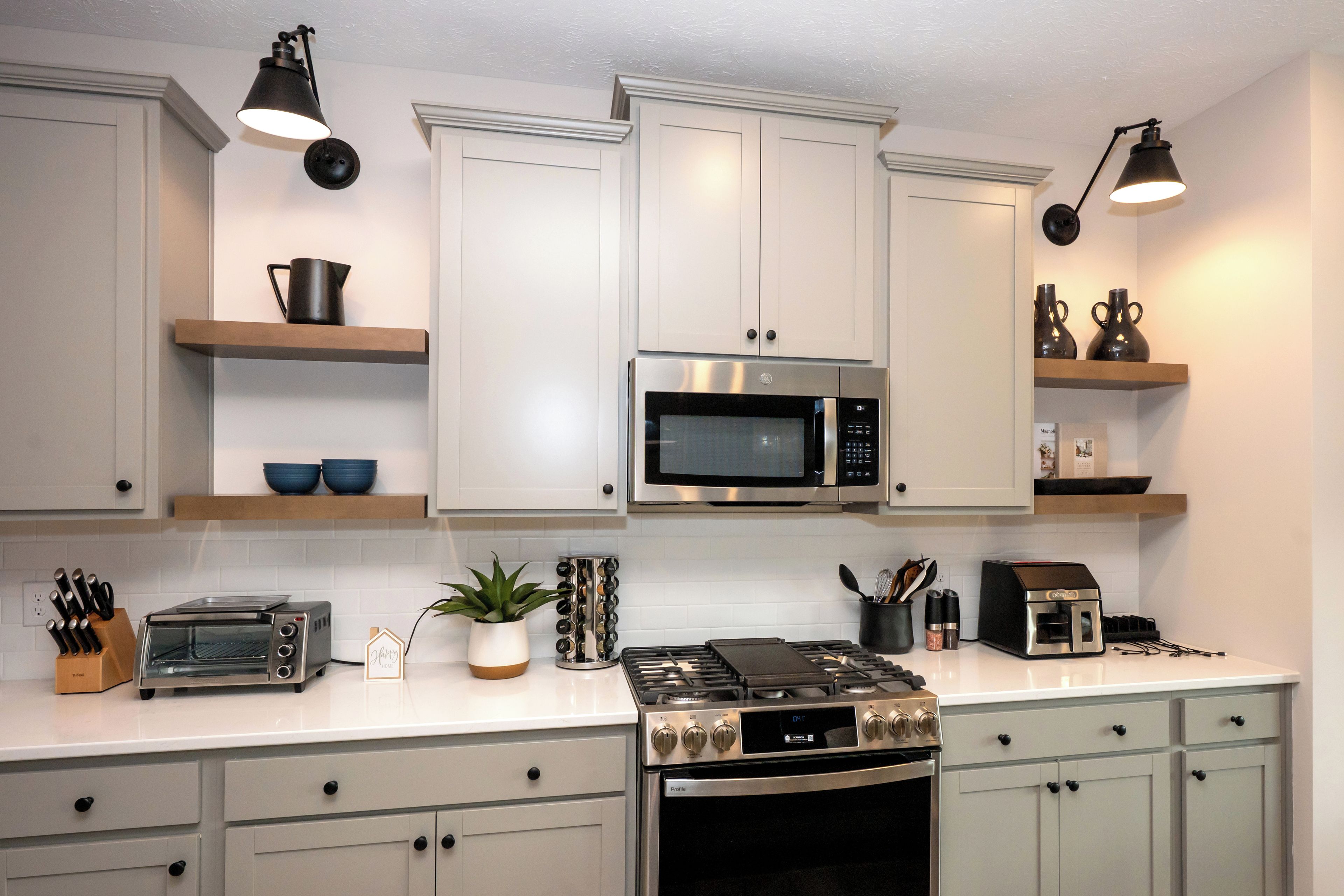 Une cuisine moderne avec des meubles blancs, un four à micro-ondes encastré, une cuisinière et un grille-pain.