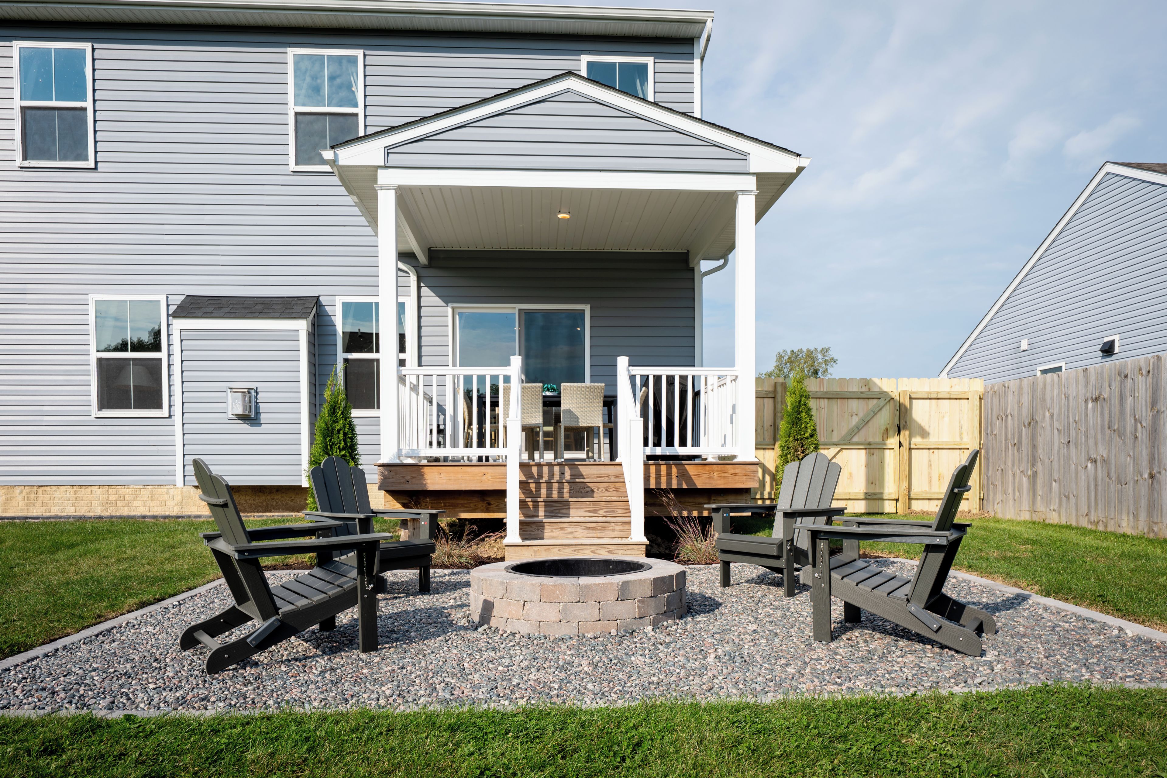 A house with a covered porch, outdoor seating, and a fire pit.