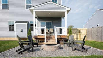 A house with a covered porch, outdoor seating, and a fire pit.