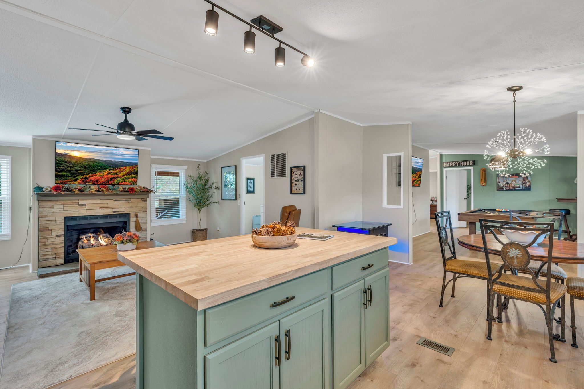 A spacious kitchen with a central island, a dining area with a pool table, and a living room with a fireplace.