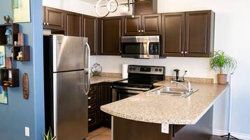 A modern kitchen with stainless steel appliances, granite countertops, and dark wooden cabinets.