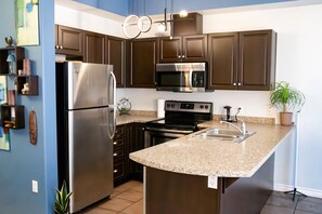 Una cocina moderna con electrodomésticos de acero inoxidable, encimeras de granito y armarios de madera oscura.