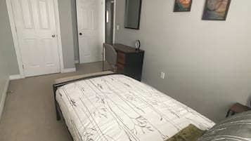 A bedroom with a bed, a desk, and two paintings on the wall.