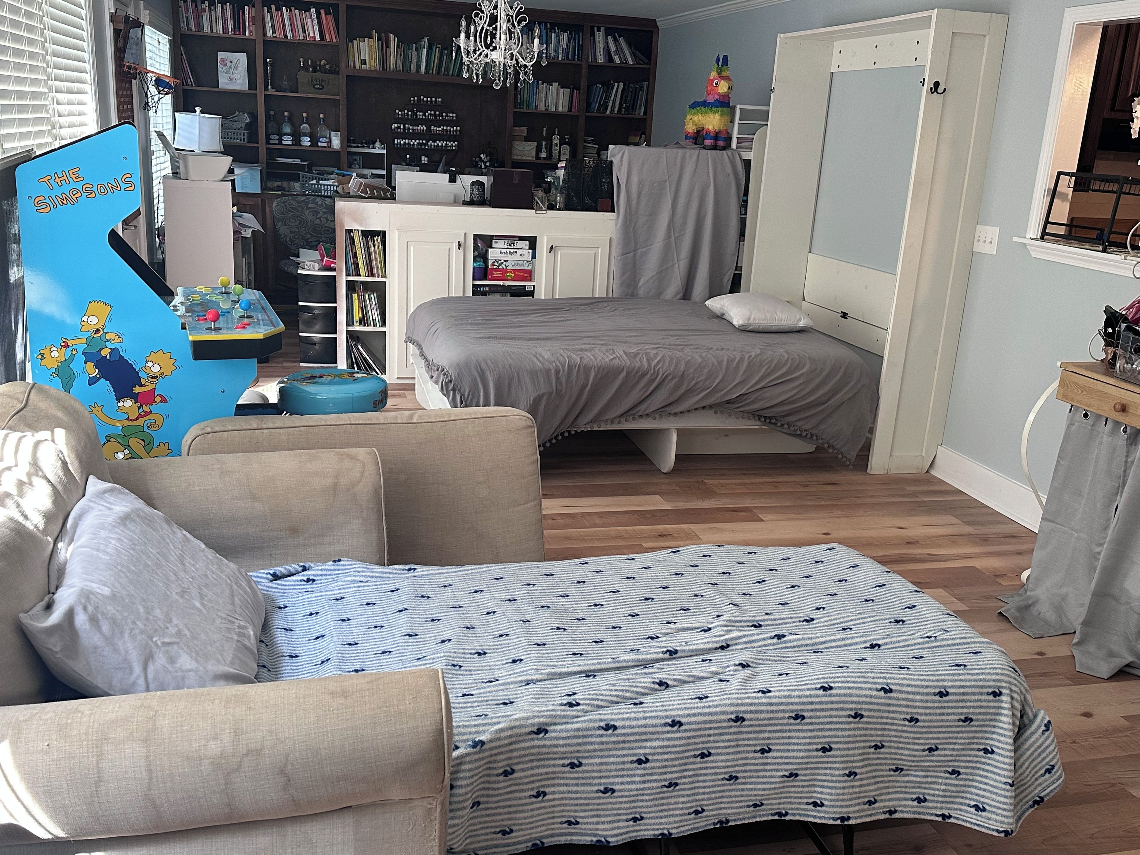A compact room with a bed, a sofa, a small table, and a bookshelf filled with books.