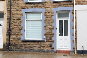 A building with a stone facade, a window with a shutter, and a door with a glass panel.