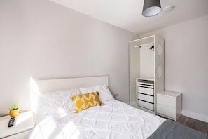 Ein Schlafzimmer mit Bett, Nachttisch, Spiegel und Kleiderschrank.