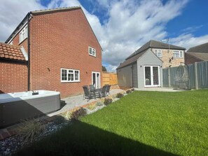 En bostadsfastighet med ett hus i tegel, en bubbelpool och en uteplats med utemöbler.