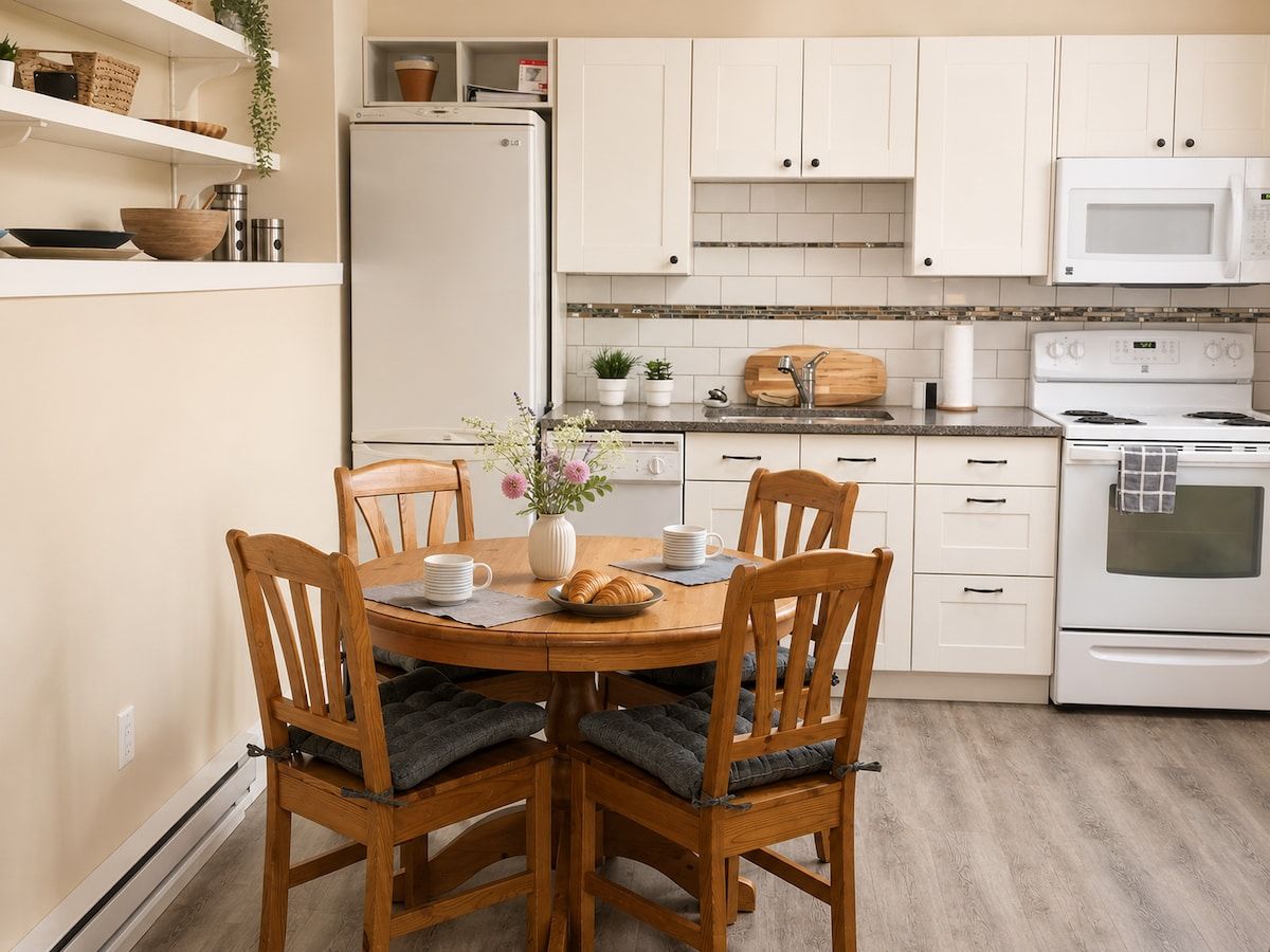 A kitchen with white cabinets, a microwave, an oven, and a dining table with chairs.
