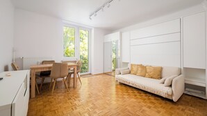 A modern living space with a dining area, sofa, and large windows. - Astronautów Chopin Airport Apartment (Warszawa)