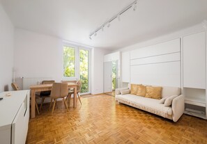Ein stilvolles Wohnzimmer mit Essbereich, Sofa und großen Fenstern.