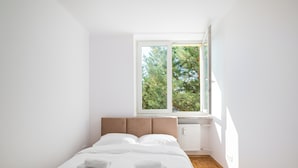 A bedroom with a bed, a window, and a radiator. - Astronautów Chopin Airport Apartment (Warszawa)