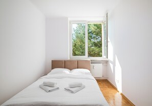 Ein Schlafzimmer mit einem Bett, einem Fenster und einer Heizung.