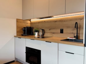 Una cuina moderna amb forn integrat, cafetera, tetera i un rentapelats.