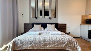 Un dormitorio moderno con una cama grande, un cabecero de madera, un escritorio empotrado y un aire acondicionado de pared.