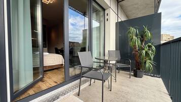 Een balkon met een bed, een tafel, stoelen en een plant in een pot.