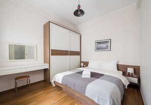 A hotel room with a bed, bedside table, lamp, and a mirror. - Metro Politechnika Spacious Apartment (Warszawa)
