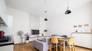 Una cucina moderna con forno integrato, zona pranzo con tavolo e sedie, divano e TV a parete.
