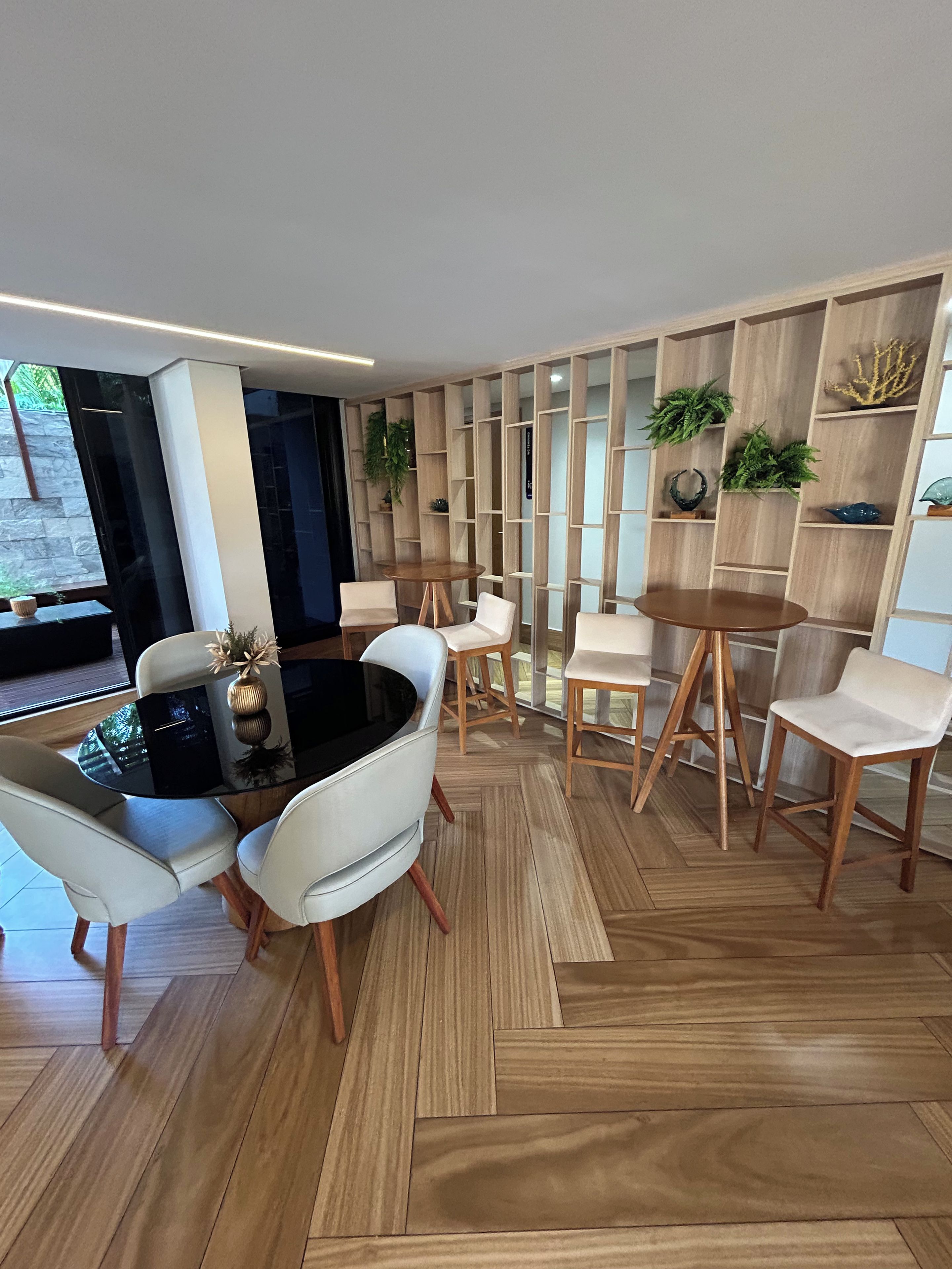 Un espace repas moderne avec une table ronde, des chaises blanches et un plancher en bois.
