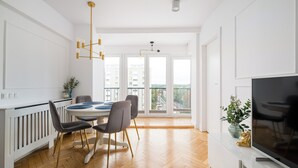 Moderni keittiö, jossa on ruokailutila, suuret ikkunat ja litteänäyttöinen televisio.