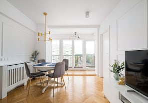 A modern kitchen with a dining area, large windows, and a flat-screen TV. - Wola Spacious Signature Apartment (Warszawa)