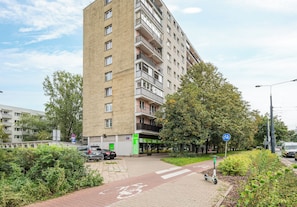 A multi-story residential building with a parking area and a designated bike lane. - Wola Spacious Signature Apartment (Warszawa)