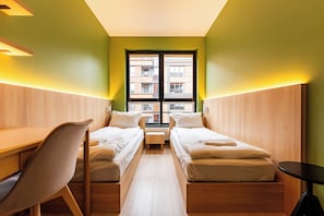Quarto de hotel com duas camas, uma escrivaninha e uma cadeira.