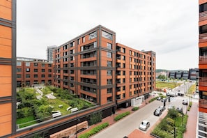 Edifício residencial de vários andares com design moderno, apresentando varandas e um jardim no terraço.