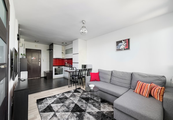 A modern living room with a grey sofa, a black and white patterned rug, and a red pillow. - Solec Powiśle Signature Apartment (Warszawa)