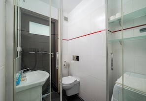 A compact bathroom with a glass shower enclosure, a toilet, and a sink. - Solec Powiśle Signature Apartment (Warszawa)