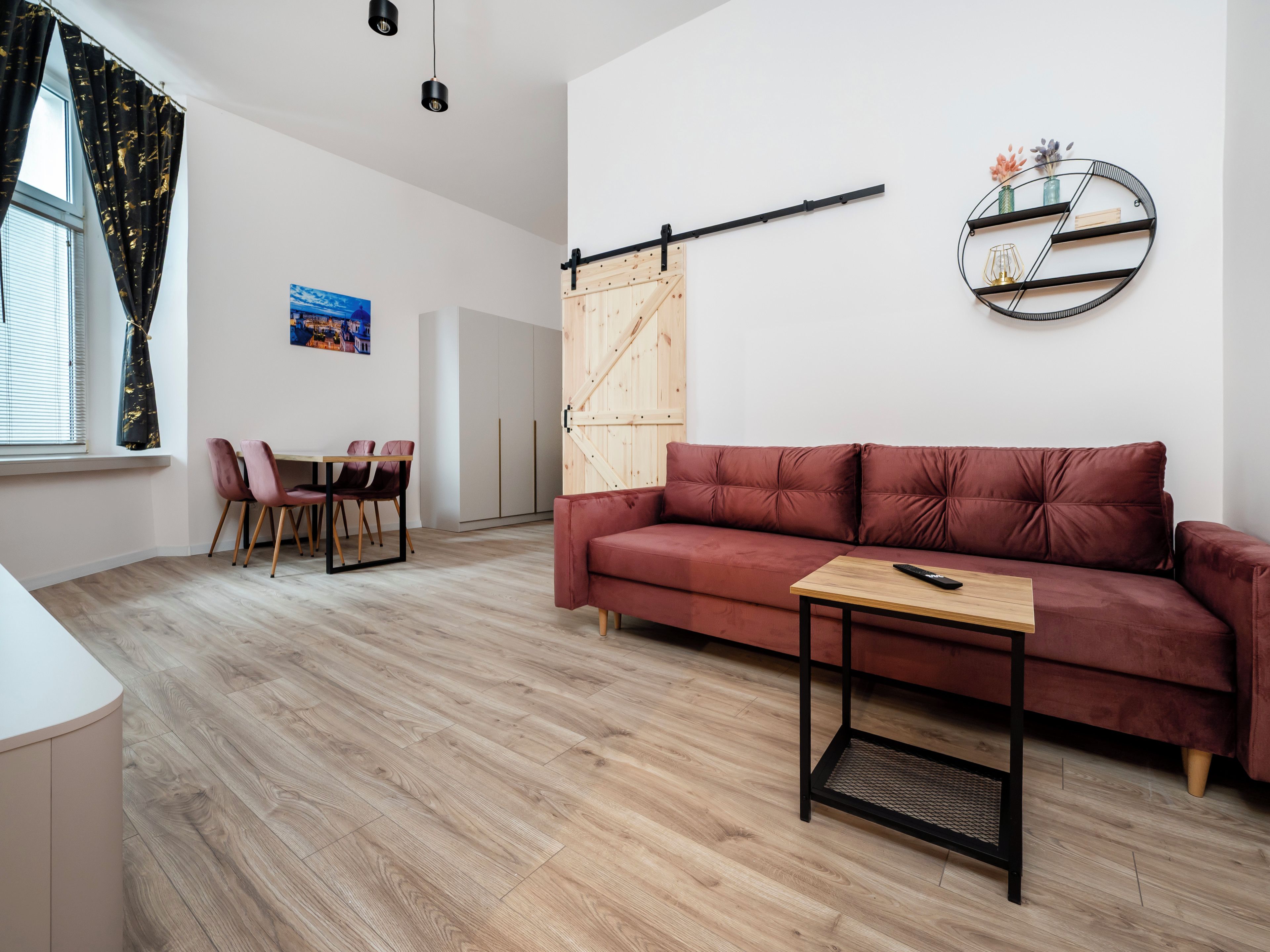 Un salon moderne comprenant un canapé, une table basse, un coin repas avec des chaises, une étagère murale et une porte coulissante.