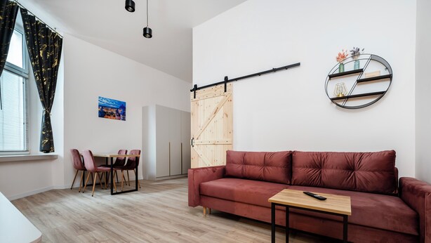 Ein modernes Wohnzimmer mit Sofa, Couchtisch, Essbereich mit Stühlen, einer Wandregal und einer Schiebetür.