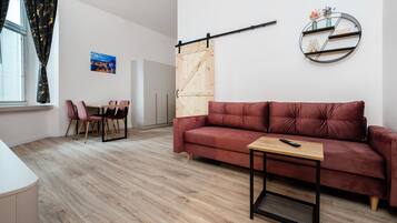 Un salon moderne comprenant un canapé, une table basse, un coin repas avec des chaises, une étagère murale et une porte coulissante.