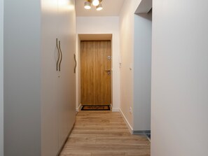 A hallway with a wooden door, a light switch, and a telephone on the wall. - Plac Wolności Homely Apartment (Łódź)