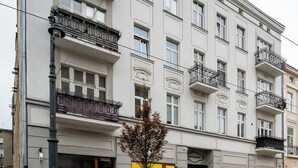 Ein mehrstöckiges Gebäude mit Balkonen, einer Straßenlaterne und einem Baum davor.