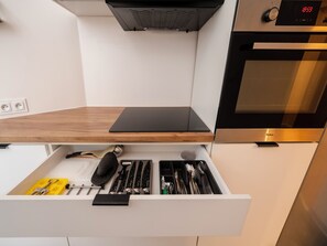 A kitchen with a built-in oven, a digital clock, and a drawer with utensils. - Plac Wolności Homely Apartment (Łódź)