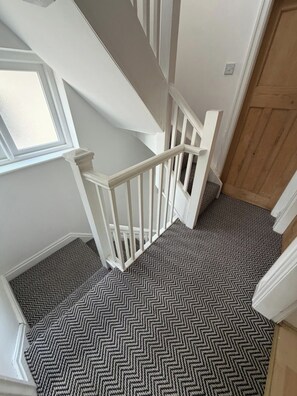 Eine Treppe mit weißen Geländern und einem schwarz-weißen Teppich.